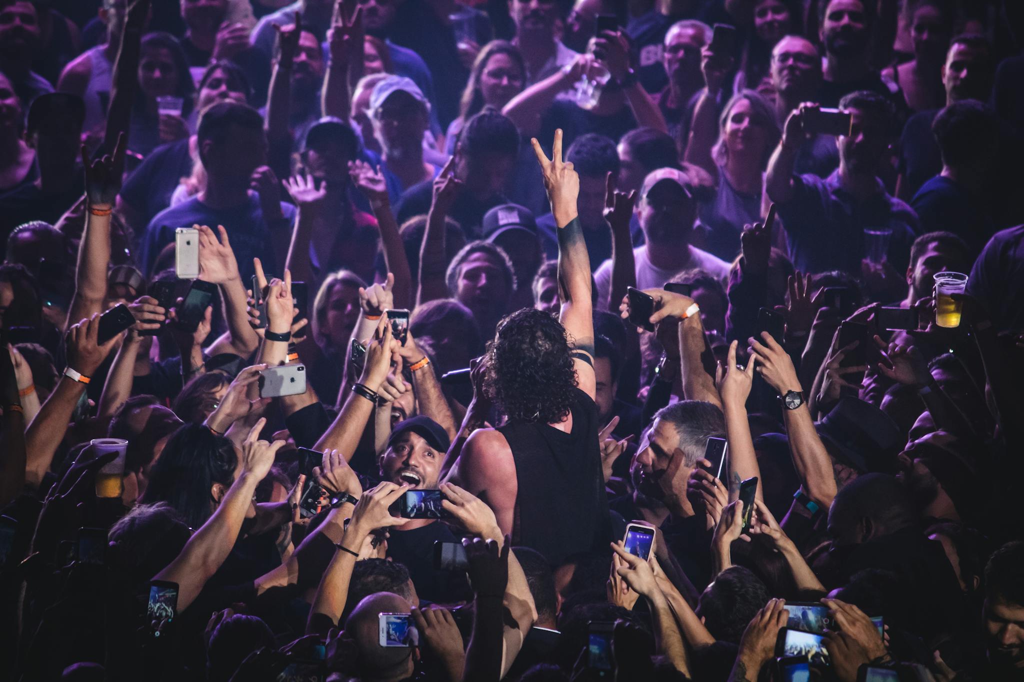 Vibrant crowd at a live concert with a performer engaging the audience, creating an electric atmosphere.